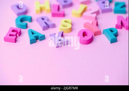 several colored wooden letters on pink background Stock Photo