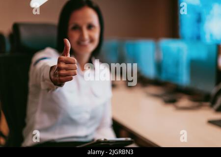 Portrait of female security operator while working in a data system control room offices Technical Operator Working at workstation with multiple Stock Photo