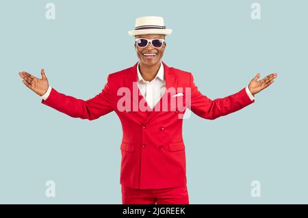Joyful extravagant dark-skinned man in a suit spreads his arms welcoming and greeting you. Stock Photo