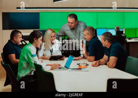 Group of security guards sitting and having briefing In the system control room They're working in security data center surrounded by multiple Screens Stock Photo