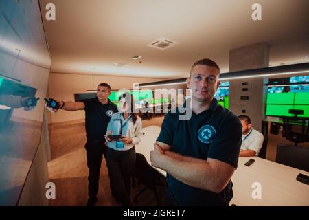 Group of Security data center operators working in a CCTV monitoring room looking on multiple monitors Officers Monitoring Multiple Screens for Stock Photo