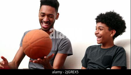 Brothers bonding together with basketball. Mixed race, black ethnicity siblings playing and spinning ball Stock Photo