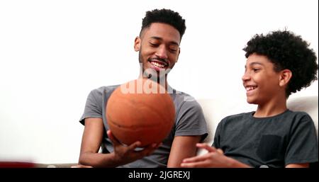 Brothers bonding together with basketball. Mixed race, black ethnicity siblings playing and spinning ball Stock Photo