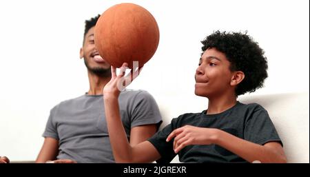 Brothers bonding together with basketball. Mixed race, black ethnicity siblings playing and spinning ball Stock Photo