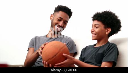 Brothers bonding together with basketball. Mixed race, black ethnicity siblings playing and spinning ball Stock Photo