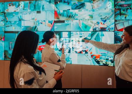 Group of female security operators working in a data system control room Technical Operators Working at workstation with multiple displays, security Stock Photo