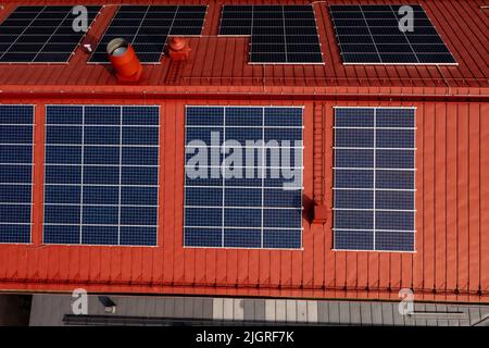 Aerial view above solar panels on a red building rooftop - birdseye, drone shot Stock Photo