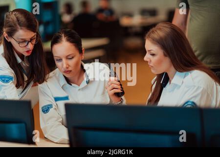 Group of female security operators working in a data system control room Technical Operators Working at workstation with multiple displays, security Stock Photo