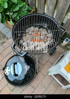 A vertical shot of lit hot coal briquettes in the black grill in the garden Stock Photo