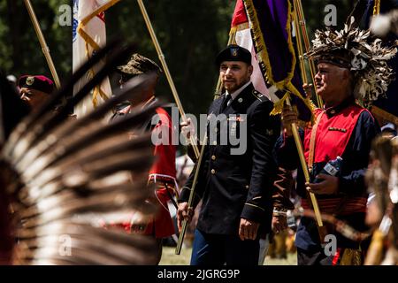 Kahnawake, Canada. 10th July, 2022. Participants hold flags at the entrance to honor military veterans during the festival. The 30th Annual Echoes of a Proud Nation pow-wow brought in thousands of people from all across North America to celebrate Native people culture and traditions in the Mohawk Reserve of Kahnawake. After a two-year hiatus, the biggest pow-wow in Quebec offered a time to meet, dance, sing, visit and celebrate with friends and family. (Credit Image: © Giordanno Brumas/SOPA Images via ZUMA Press Wire) Stock Photo