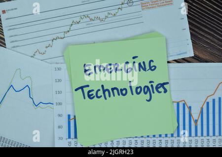 Concept of Emerging Technologies write on sticky notes isolated on Wooden Table. Stock Photo