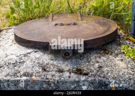 A rusty manhole cover bearing the inscription "POUS" on a stone in Rue de la Porte de Lambre, Die, France. Mirabel was once a fortified high village (village perché) in France Stock Photo