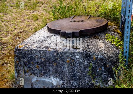 A rusty manhole cover bearing the inscription "FOUG" rests on a concrete block near the ruins of Mirabel, Mirabel-et-Blacons, Drôme, France. Stock Photo