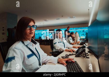 Group of female security operators working in a data system control room Technical Operators Working at workstation with multiple displays, security Stock Photo
