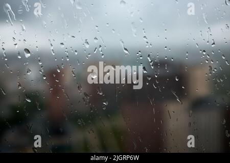 Drops on glass on rainy cloudy day evoke melancholy and sadness. View of city from the window. Selective focus Stock Photo