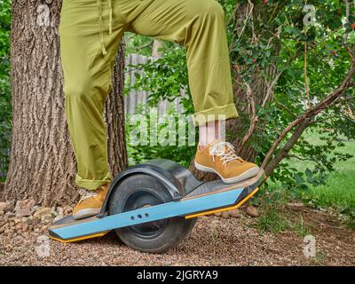riding one-wheeled electric skateboard in a backyard or park Stock Photo