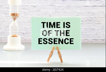 Closeup on businessman holding a card with TIME IS OF THE ESSENCE message Stock Photo