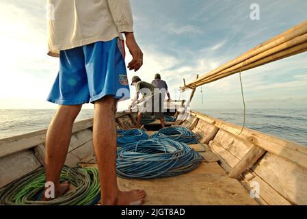 Whale hunters on traditional whaling boat equipped with bamboo harpoons and ropes, that is sailing on Savu Sea off the coast of Lamalera in Wulandoni, Lembata, East Nusa Tenggara, Indonesia. Stock Photo