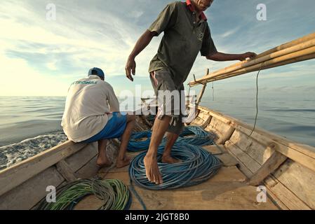 Whale hunters on traditional whaling boat equipped with bamboo harpoons and ropes, that is sailing on Savu Sea off the coast of Lamalera in Wulandoni, Lembata, East Nusa Tenggara, Indonesia. Stock Photo