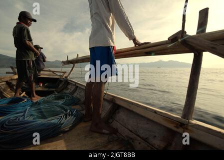 Whale hunters scouting around to find a sign of whale as they are standing on traditional whaling boat that is sailing on Savu Sea off the coast of Lamalera in Wulandoni, Lembata, East Nusa Tenggara, Indonesia. Stock Photo