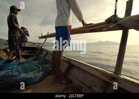 Whale hunters scouting around to find a sign of whale as they are standing on traditional whaling boat that is sailing on Savu Sea off the coast of Lamalera in Wulandoni, Lembata, East Nusa Tenggara, Indonesia. Stock Photo