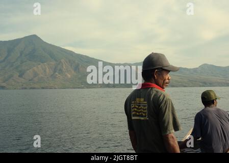 Whale hunters scouting around to find a sign of whale as they are standing on traditional whaling boat that is sailing on Savu Sea off the coast of Lamalera in Wulandoni, Lembata, East Nusa Tenggara, Indonesia. Stock Photo