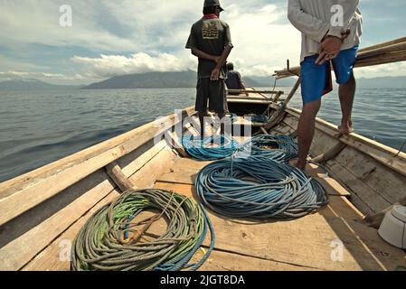 Whale hunters scouting around to find a sign of whale as they are standing on traditional whaling boat that is sailing on Savu Sea off the coast of Lamalera in Wulandoni, Lembata, East Nusa Tenggara, Indonesia. Stock Photo