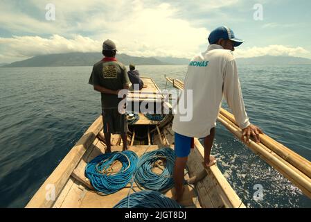 Whale hunters scouting around to find a sign of whale as they are standing on traditional whaling boat that is sailing on Savu Sea off the coast of Lamalera in Wulandoni, Lembata, East Nusa Tenggara, Indonesia. Stock Photo