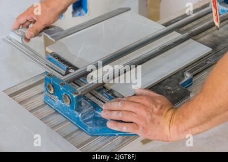 Construction worker cutting ceramic tile floor with manual tools on a ceramic tile floor of equipment for laying ceramic tiles Stock Photo
