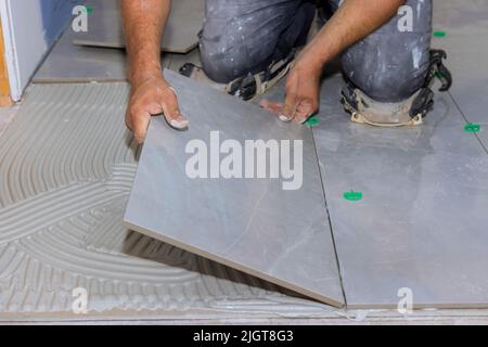 Working on an adhesive surface while installing ceramic floor tiles Stock Photo
