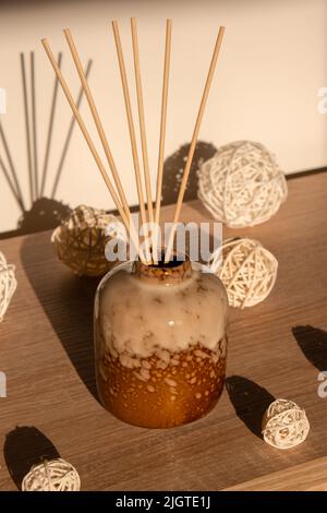 Cozy home decorations aroma reed diffuser in the living room. Home comfort concept. Bottle container with wood stick diffusers Essential oils to scent your home Minimalist air freshener concept. Romantic and relax ambient. Decoration, hygge and cosiness concept Stock Photo