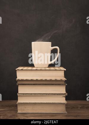 Cup of hot coffee on top of a stack of old books Stock Photo