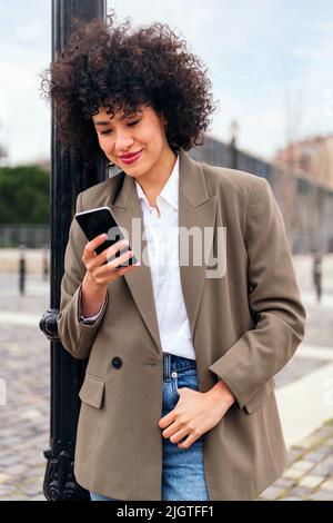 smiling young latin woman checking her phone Stock Photo