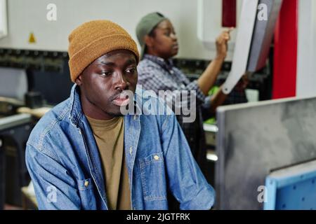African operator choosing program on computer machine while working at plant Stock Photo