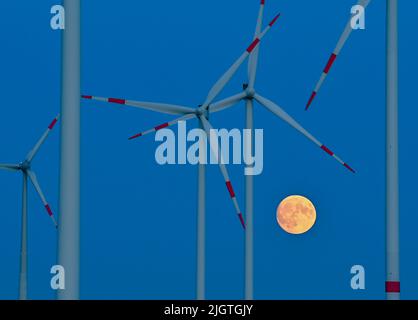 Sieversdorf, Germany. 12th July, 2022. The moon, which is about 95 percent visible and waxing, glows yellowish in the sky between wind turbines shortly after sunset. On the night of July 13, 2022, a super full moon can be seen in the sky if visibility is good. At moonrise around 10 p.m., the Earth's satellite will be 357,517 kilometers from Earth. Despite this distance, it will be the largest supermoon of the year. Credit: Patrick Pleul/dpa/Ģ����ý Live News Stock Photo