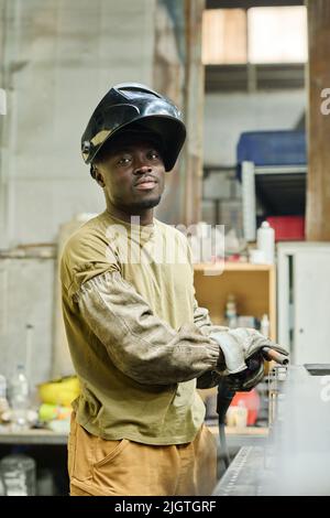 Portrait of African industrial welder looking at camera while working with welding torch at factory Stock Photo