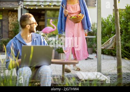 Happy young family with laptop and healthy lunch at backyard Stock Photo