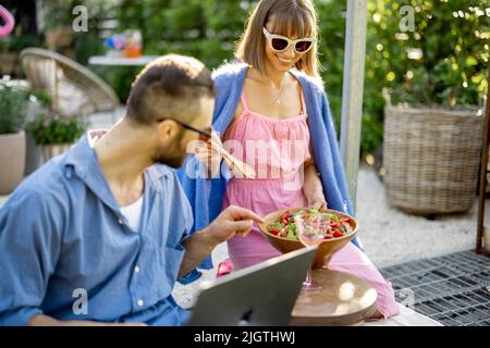 Happy young family with laptop and healthy lunch at backyard Stock Photo