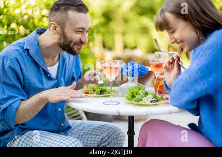 Young man and woman eating healthy food, spending summer time together outdoors Stock Photo