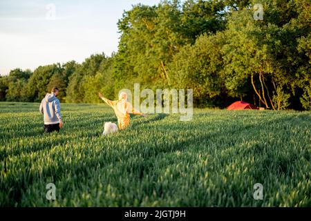 Carefree couple walk on a green field on sunset Stock Photo