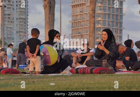 Palestinians gather at Charles Clore beachfront park during the Muslim holiday of Eid al-Adha on July 11, 2022 in Tel Aviv, Israel. Israeli authorities permitted travel for West Bank Palestinians to visit Tel Aviv and other places in Israel during Eid al-Adha holiday. Stock Photo