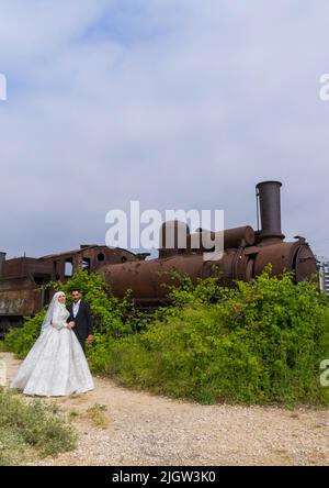 Newly wedded couple in front of Old locomotive from Beirut–Damascus line, North Governorate, Tripoli, Lebanon Stock Photo
