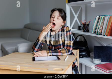 Bored secondary school girl yawning. Young learner tired of studying, reading books and classes. Young learner wants to take a brake and have some res Stock Photo