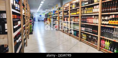 An aisle in a supermarket or off-licence with alcoholic drinks on the shelves, and no people Stock Photo