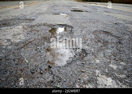 water filled potholes in the middle of a road in england uk Stock Photo