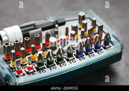 A set of metal power bits in a box on a gray background, for repair and maintenance Stock Photo