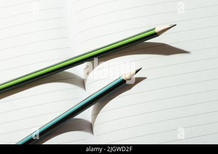 A pair of pencils on an open notebook. Stock Photo