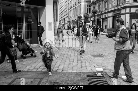 05-09-2016  Nantes , France.   A man blows soap bubbles, and a child is fascinated by this in the Rue of Nantes. Stock Photo