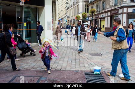 05-09-2016  Nantes , France.   A man blows soap bubbles, and a child is fascinated by this in the Rue of Nantes. Stock Photo