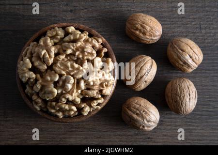Peeled walnuts and whole walnuts on wooden background Stock Photo